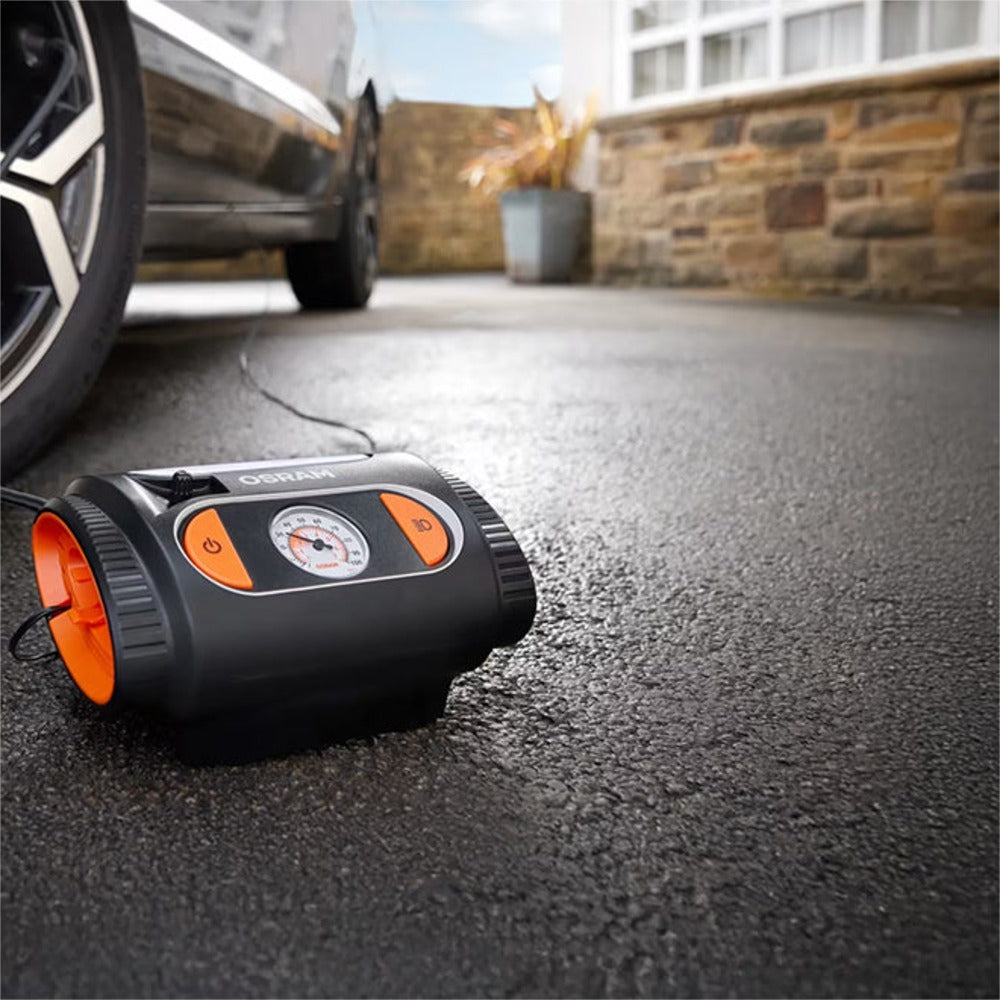 Osram TYREinflate 2110 kompressor på indkørsel forbundet til bil i baggrunden