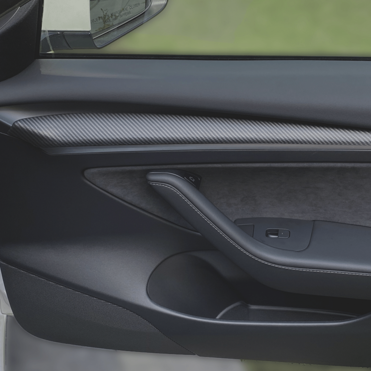 Dørcover i carbon-look monteret på dørpanelet i en Tesla Model 3/Y
