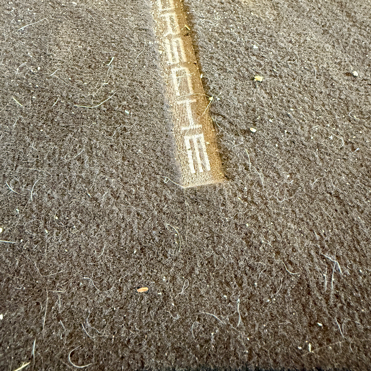 Før billede af møgbeskidt bilmåtte med Porsche logo før TurboClean støvsuger