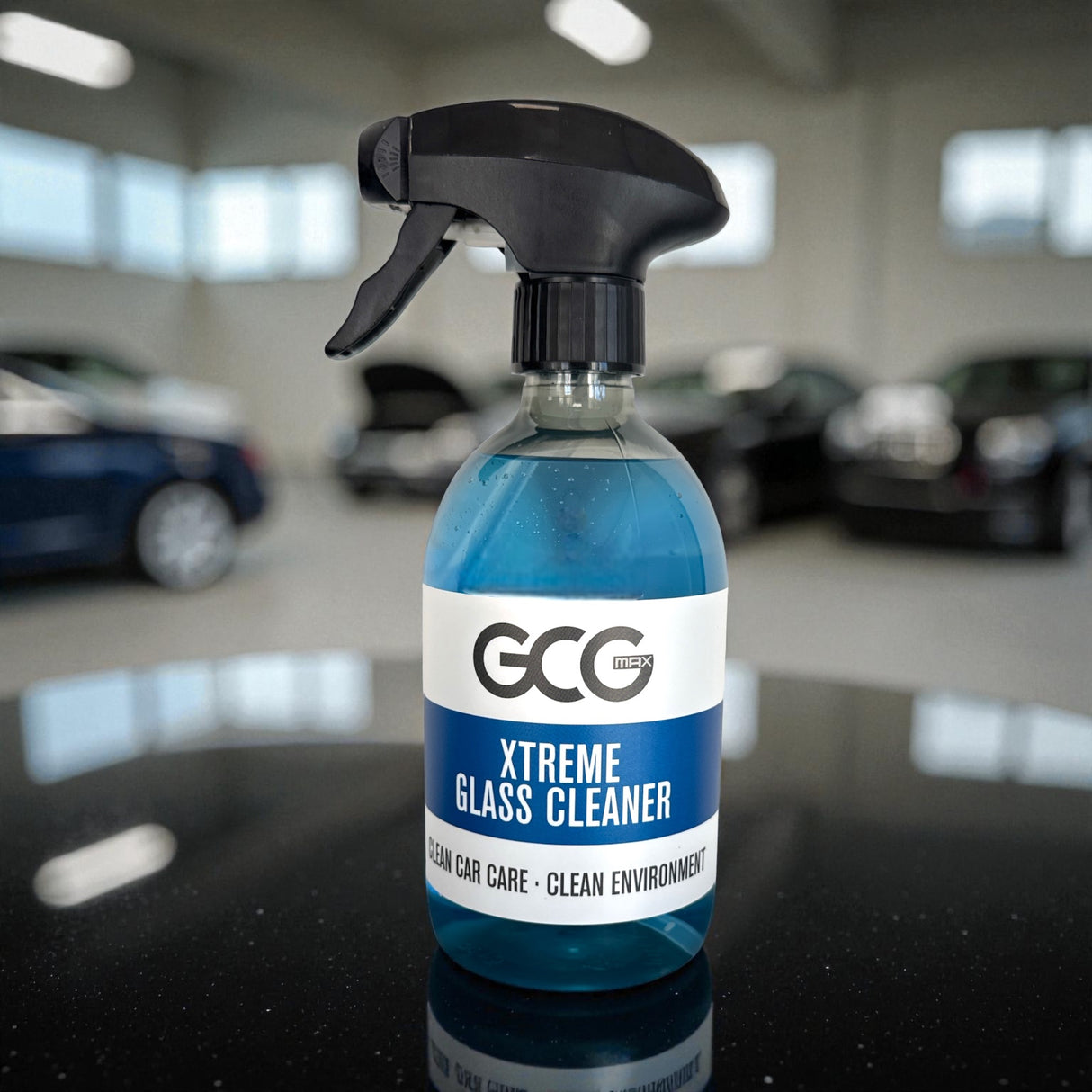 GCG MAX Xtreme Glass Cleaner spray i blå flaske på bord med biler i baggrunden