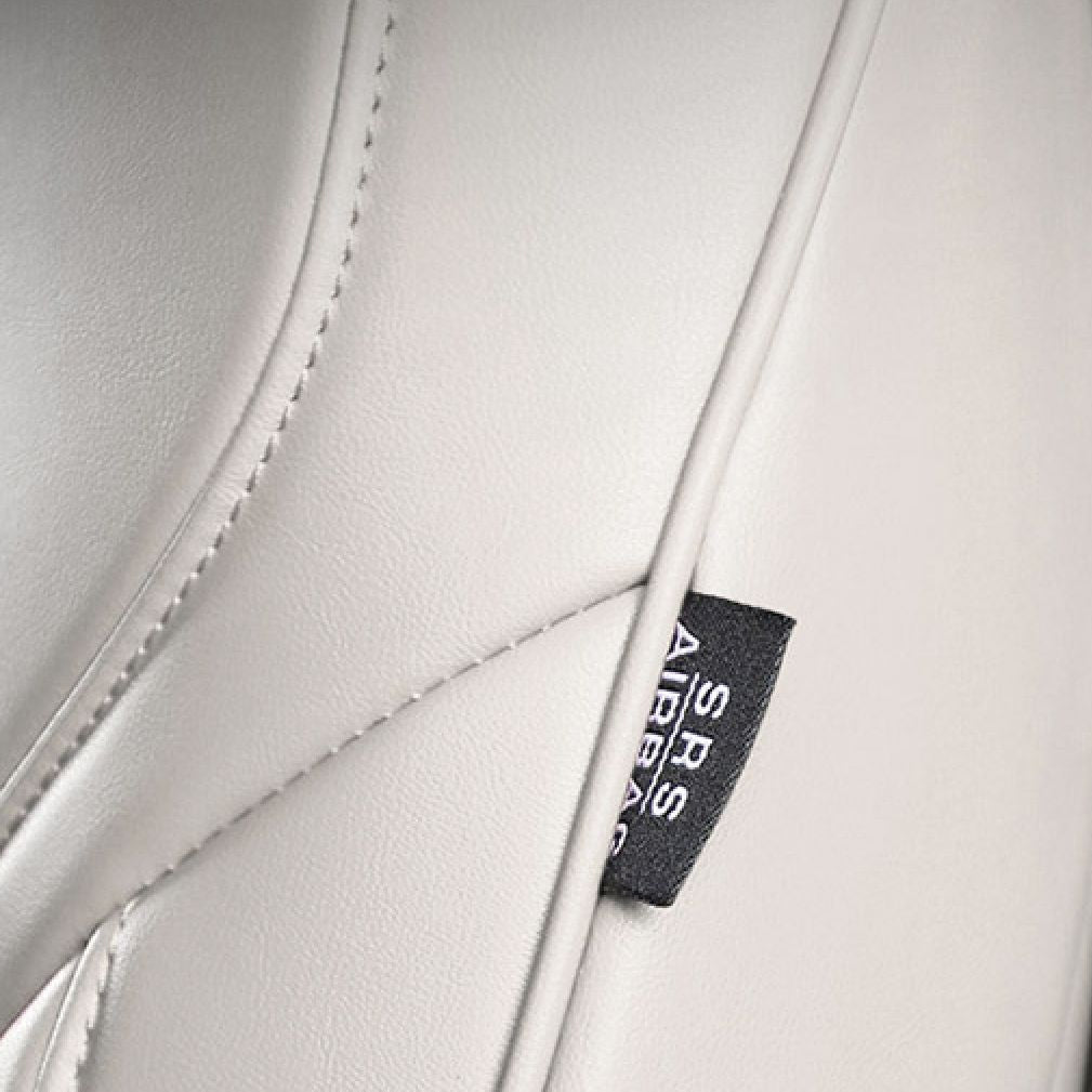 Nærbillede af det hvide læder-sædeovertræks sømme og et SRS Airbag-mærke i siden