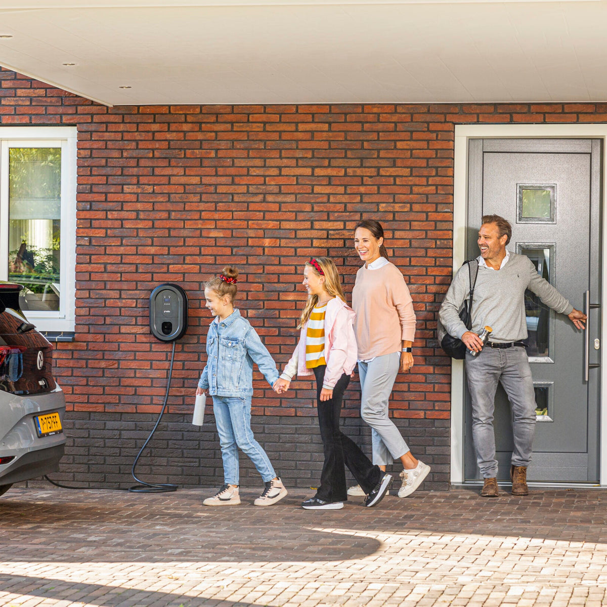 Familie ankommer hjem til Ratio ladeboks og elbil, der er tilsluttet