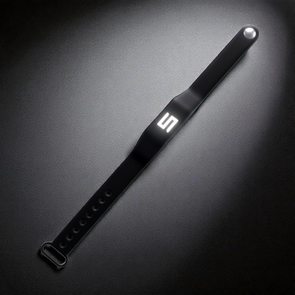 Sort Tesla Key armbånd med Tesla-logo, lagt diagonalt på mørk baggrund