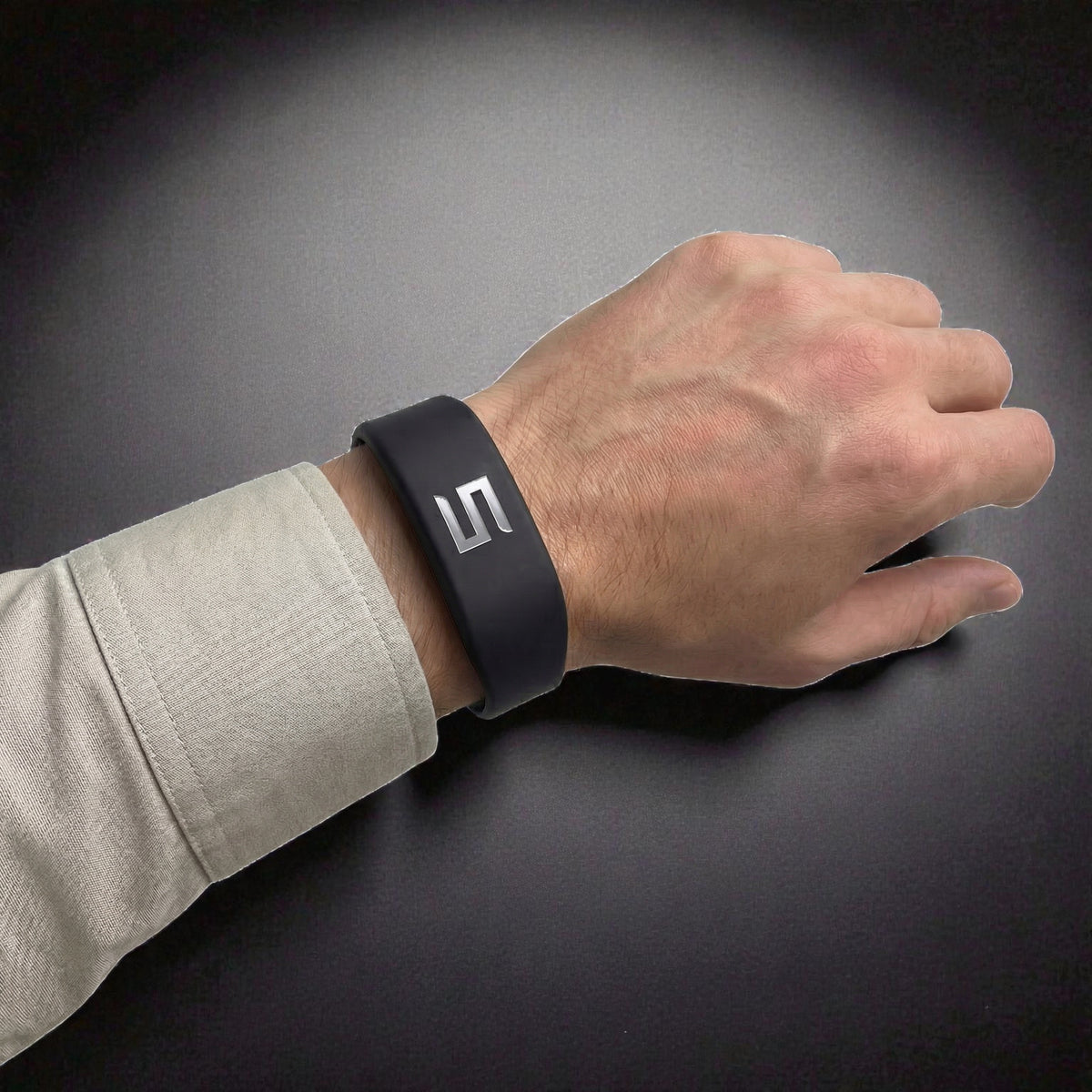 Sort Tesla Key armbånd med Tesla-logo, båret på håndled, nærbillede