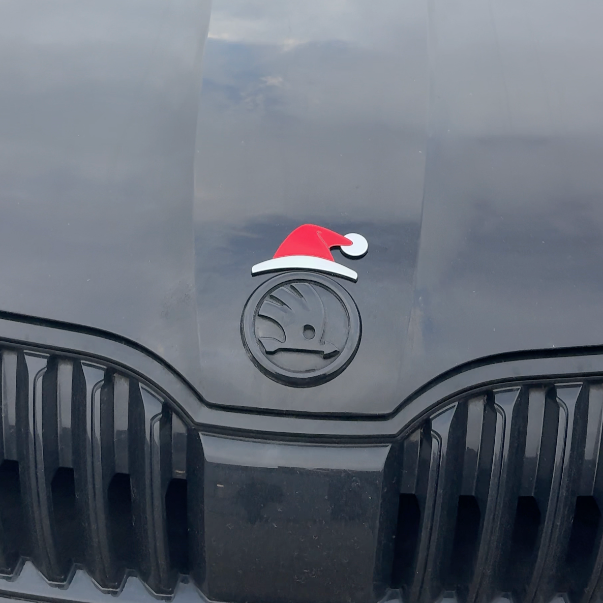 Rød og hvid nissehue monteret på Skoda-emblem foran på bilens kølergrill