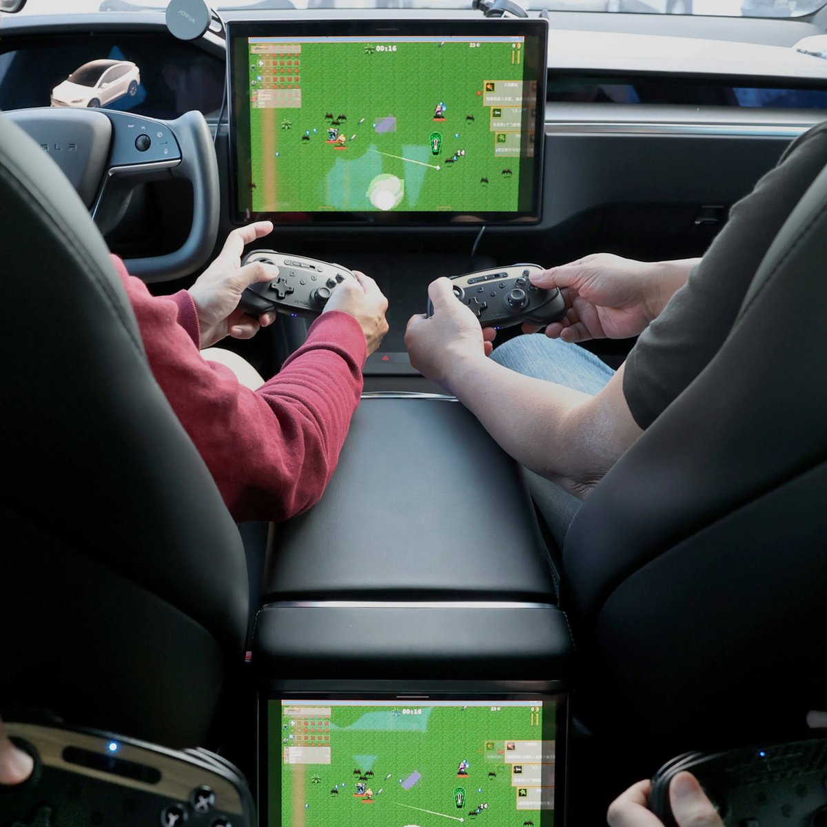 To personer spiller med trådløse controllere på Teslaens midterskærm