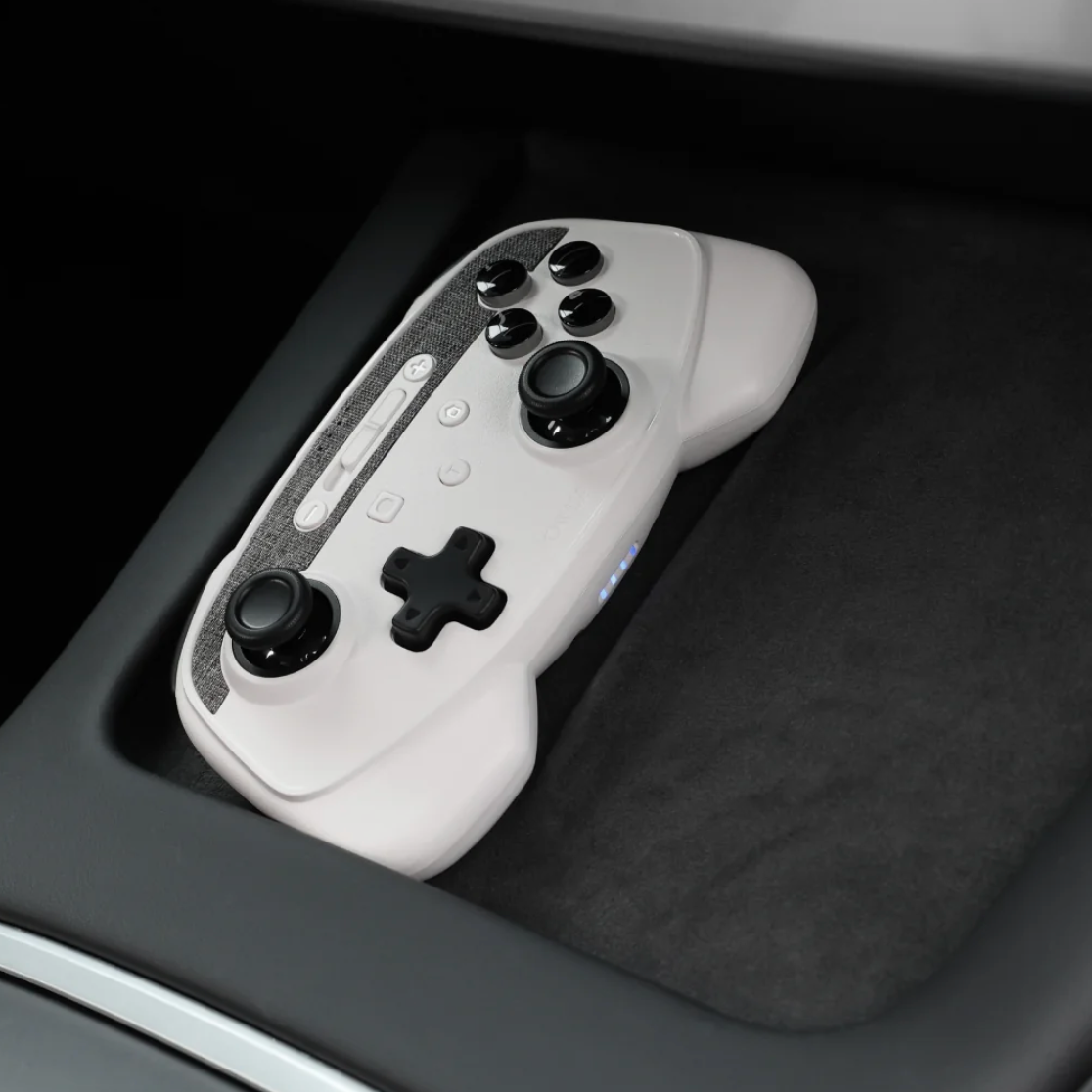 Hvid trådløs controller placeret i Teslaens trådløse opladerbakke i centerkonsollen