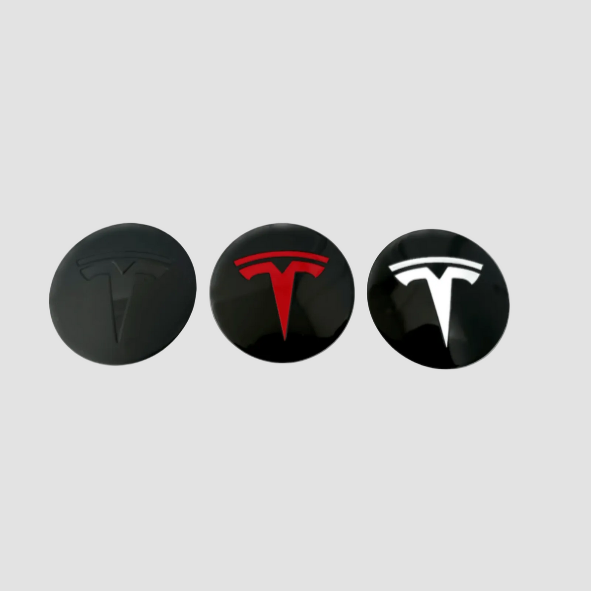 Tre Tesla centerkapsler i sort, rød og hvid til fælge.