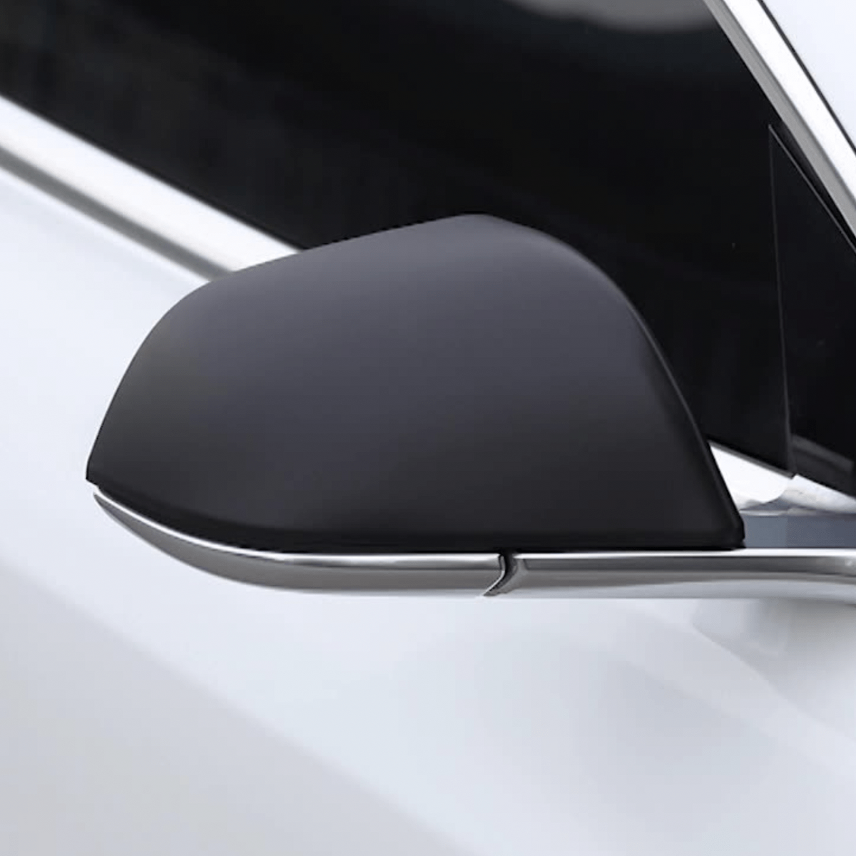 Mat sort cover monteret på sidespejlet på en hvid Tesla Model 3