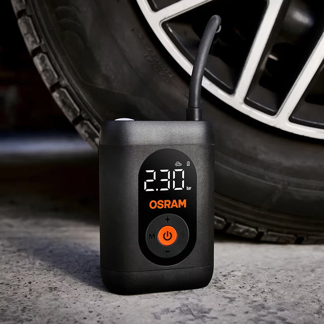 Osram TYREinflate 1600 stående på asfalt ved siden af bildæk, display viser 230 kPa