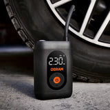 Osram TYREinflate 1600 stående på asfalt ved siden af bildæk, display viser 230 kPa
