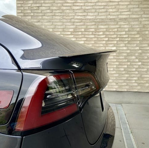 ABS-spoiler med carbon-look coating på bagklappen af en sort Tesla Model Y, med baglygte synlig