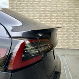 ABS-spoiler med carbon-look coating på bagklappen af en sort Tesla Model Y, med baglygte synlig