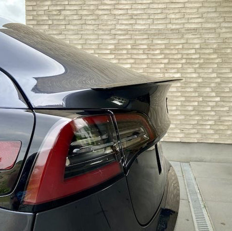 ABS-spoiler med carbon-look coating på bagklappen af en sort Tesla Model Y, med baglygte synlig