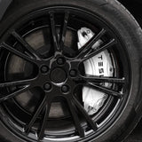 Hvidt cover til bremsekaliber med TESLA-tekst monteret bag fælgen på en Tesla Model Y
