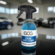 GCG MAX Xtreme Glass Cleaner spray i blå flaske på bord med biler i baggrunden
