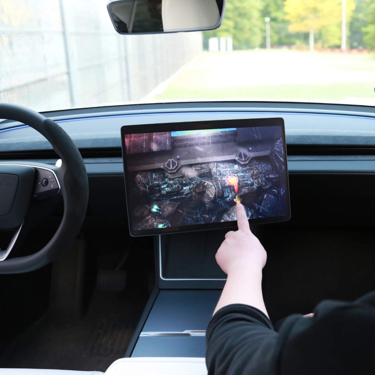Hånd der spiller et spil på den drejede Tesla-skærm med drejebeslag