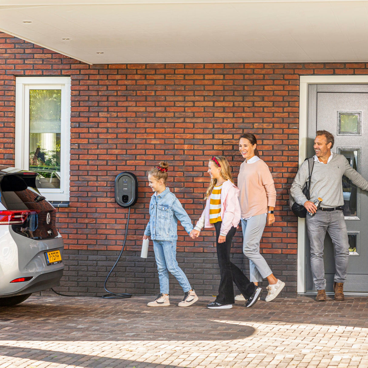 Familie forlader hus med elbil tilsluttet Ratio smart ladeboks