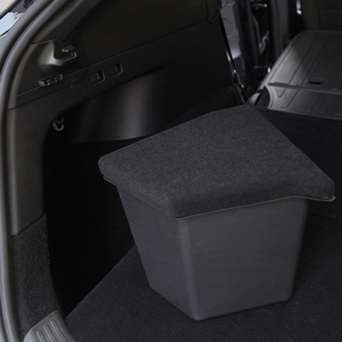 Sort opbevaringsboks med låg placeret i bagagerummet på en Tesla Model Y