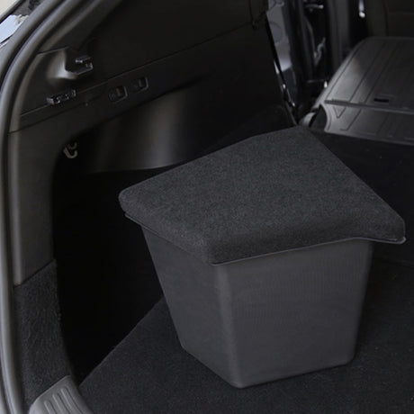 Sort opbevaringsboks med låg placeret i bagagerummet på en Tesla Model Y