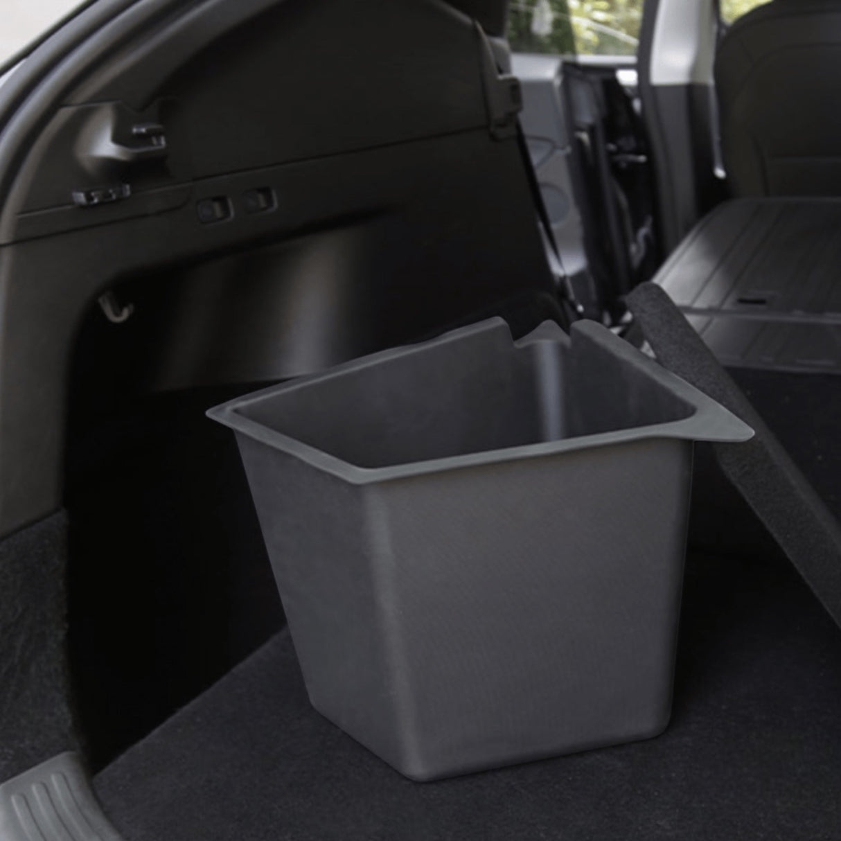 Sort opbevaringsboks med åbent låg i bagagerummet på en Tesla Model Y, med tom inderside synlig
