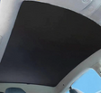 Sort solafskærmning monteret på panoramaglastaget i en Tesla Model S, set indefra