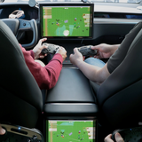 To personer spiller med trådløse controllere på Teslaens midterskærm