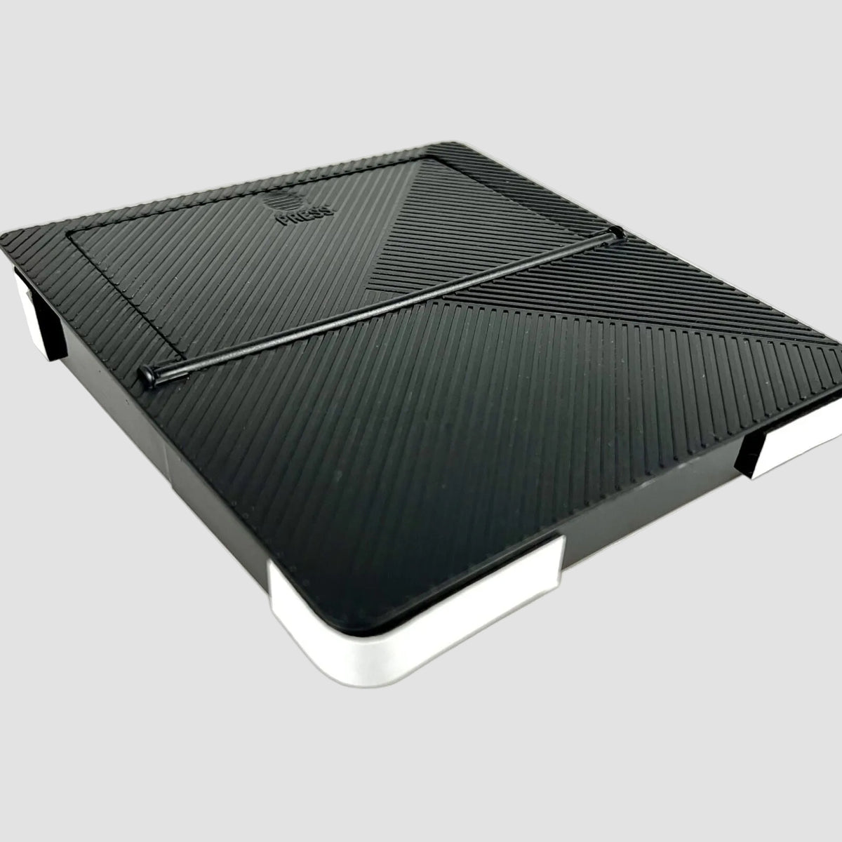 Sort skjult opbevaringsboks med ribbet låg set fra oven til Tesla Model 3/Y på lys baggrund