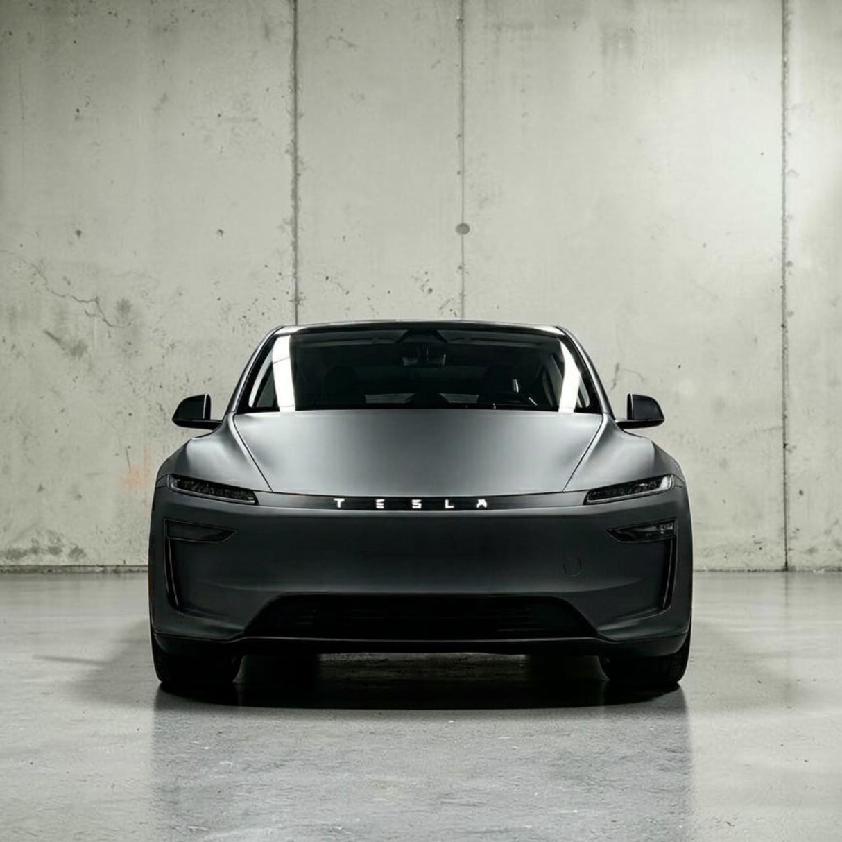Tesla Model Y 2025 Juniper set forfra i mat grå, viser TESLA logo på lystribe