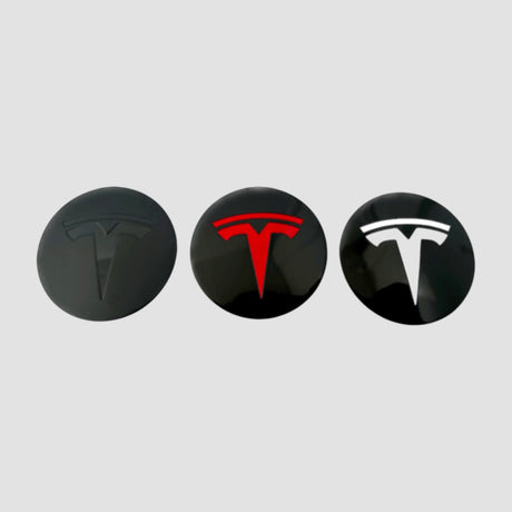 Tre Tesla centerkapsler med T-logo i sort, rødt og hvidt