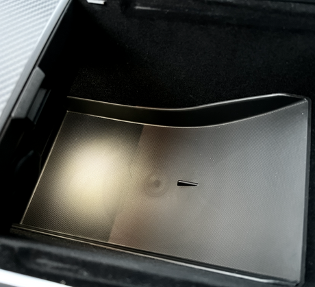 Sort tekstureret underlag/bakke placeret i opbevaringsrummet under armlænet i Tesla Model Y