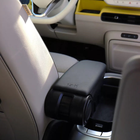 Sort RATI armlæn monteret mellem forsæderne i VW ID. Buzz med lyst interiør og gul instrumentbræt-detalje