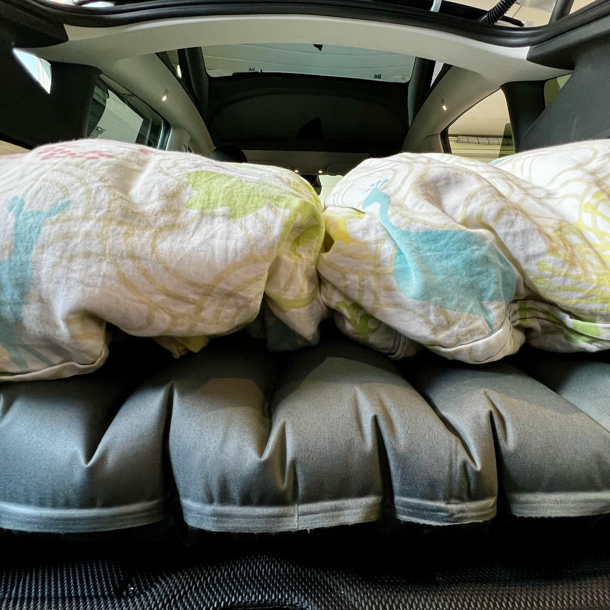 Luftmadras med sengetøj i bagagerum på en Tesla Model Y til bilferie.