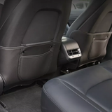 Sorte ryglænsbeskyttere med opbevaringslommer monteret på forsædernes bagside i en Tesla Model 3/Y
