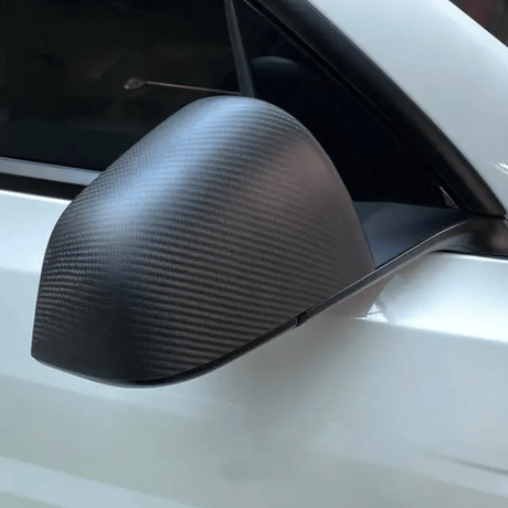 Sidespejlscover i ægte carbonfiber monteret på en hvid Tesla
