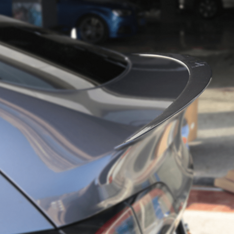 Nærbillede af blank sort spoiler monteret på bagklappen af en mørk Tesla Model Y